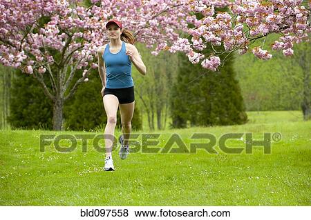 Stock Photo - Mixed race runner jogging across field. Fotosearch