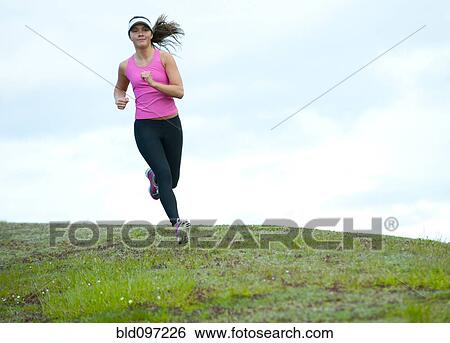 Stock Photograph - Mixed race runner jogging across field. Fotosearch