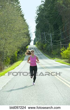 Picture - Mixed race runner training on remote road. Fotosearch
