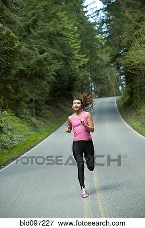 Stock Photo - Mixed race runner training on remote road. Fotosearch