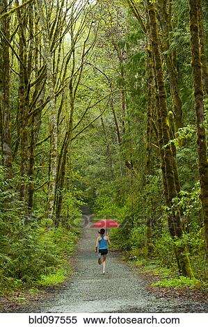 Stock Photography - Mixed race runner training on remote road with umbrella. Fotosearch