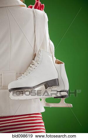 Stock Photo - Mixed race woman carrying ice skates. Fotosearch