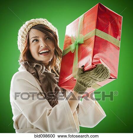 Stock Image - Mixed race woman holding Christmas gift. Fotosearch