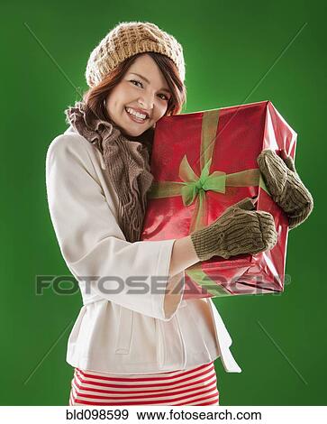Mixed race woman holding Christmas gift View Large Photo Image Stock Photo - Mixed race woman holding Christmas gift. Fotosearch