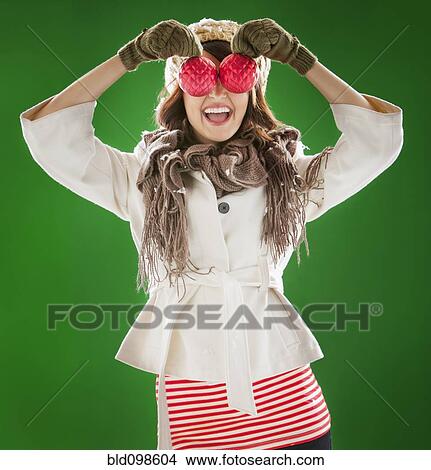 Picture - Mixed race woman holding Christmas ornaments in front of her face. Fotosearch