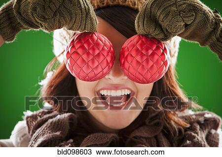 Mixed race woman holding Christmas ornaments in front of her face View Large Photo Image Stock Image - Mixed race woman holding Christmas ornaments in front of her face. Fotosearch