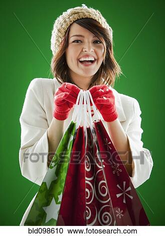 Stock Image - Mixed race woman holding Christmas shopping bags. Fotosearch