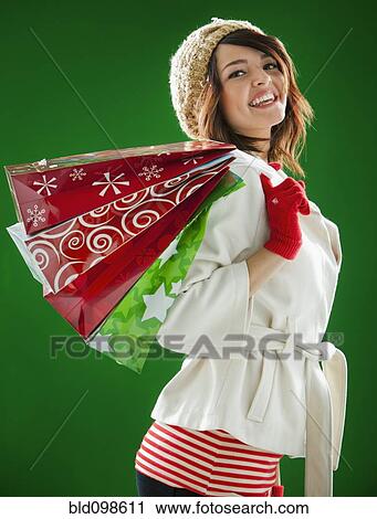 Stock Image - Mixed race woman holding Christmas shopping bags. Fotosearch