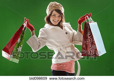 Stock Photo - Mixed race woman holding Christmas shopping bags. Fotosearch