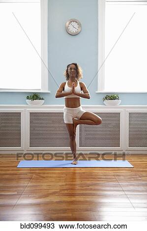 Stock Image - Mixed race woman practicing yoga. Fotosearch
