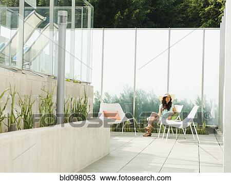 Stock Image - Mixed race woman relaxing on patio. Fotosearch