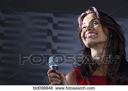 Stock Photo - Mixed race woman singing karaoke in nightclub. Fotosearch