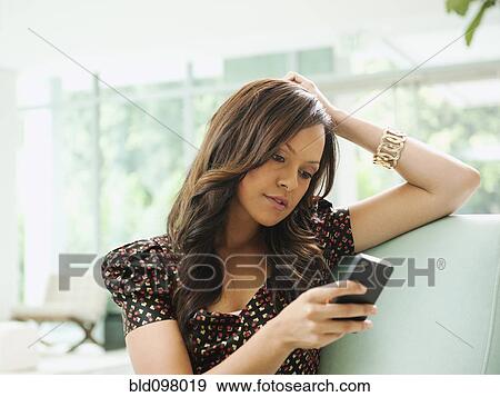 Stock Photo - Mixed race woman text messaging on cell phone. Fotosearch