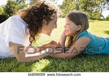 Mother and daughter laying in grass together View Large Photo Image Stock Photo - Mother and daughter laying in grass together. Fotosearch