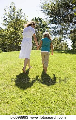 Stock Image - Mother and daughter walking and holding hands. Fotosearch