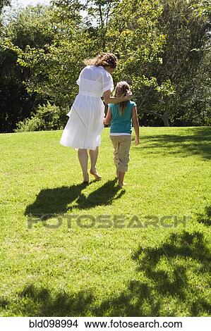 Mother and daughter walking together in grass View Large Photo Image Picture - Mother and daughter walking together in grass. Fotosearch