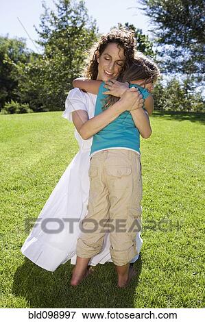 Stock Photo - Mother hugging daughter in park. Fotosearch