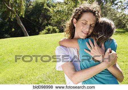 Mother hugging daughter in park View Large Photo Image Stock Photo - Mother hugging daughter in park. Fotosearch