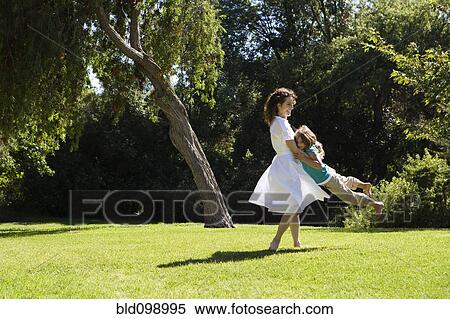 Stock Photography - Mother swinging daughter in park. Fotosearch