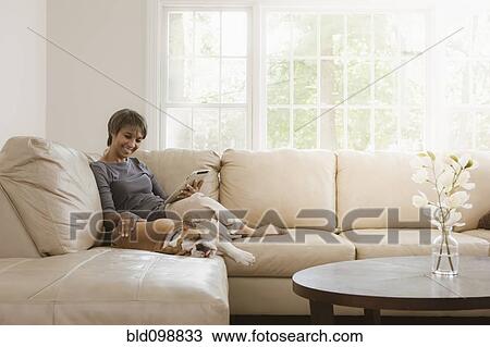 Stock Image - Native American woman relaxing on sofa with English bulldog. Fotosearch