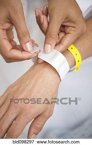 Nurse putting identification bracelet on patient in hospital View Large Photo Image Stock Photo - Nurse putting identification bracelet on patient in hospital. Fotosearch