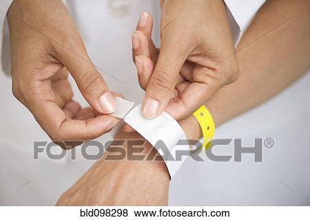 Stock Photo - Nurse putting identification bracelet on patient in hospital. Fotosearch