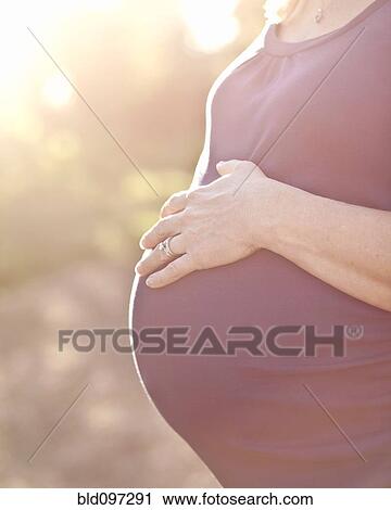 Stock Image - Pregnant Caucasian woman caressing stomach. Fotosearch