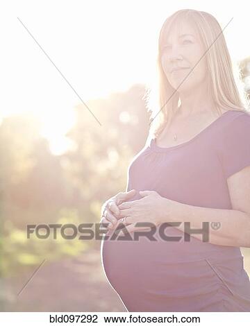Stock Image - Pregnant Caucasian woman caressing stomach. Fotosearch