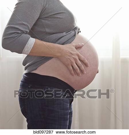 Stock Photo - Pregnant Caucasian woman caressing stomach. Fotosearch