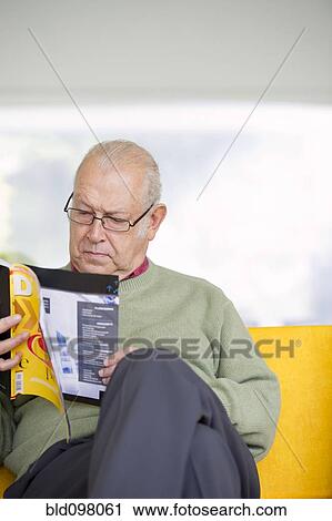 Stock Image - Senior Hispanic man reading magazine. Fotosearch