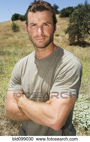 Stock Image - Serious man standing in remote field. Fotosearch