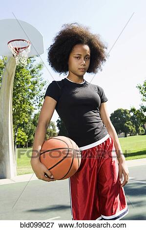 Serious teenage girl holding basketball on court View Large Photo Image Stock Photo - Serious teenage girl holding basketball on court. Fotosearch