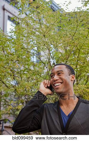 Stock Photo - Smiling Black man talking on cell phone. Fotosearch