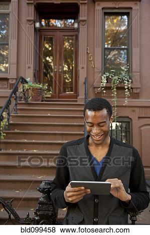 Smiling Black man using digital tablet View Large Photo Image Stock Photo - Smiling Black man using digital tablet. Fotosearch
