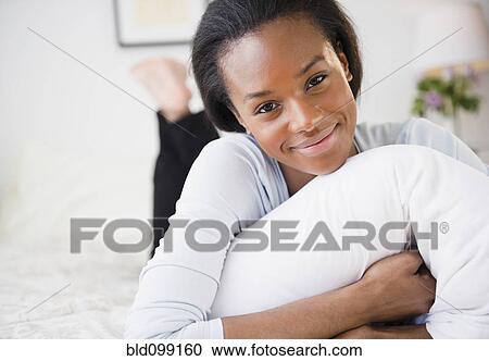 Stock Image - Smiling Black woman laying in bed. Fotosearch