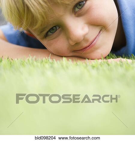 Picture - Smiling Caucasian boy laying in grass. Fotosearch