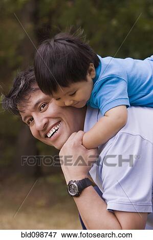 Stock Photo - Smiling father giving piggyback to baby boy. Fotosearch
