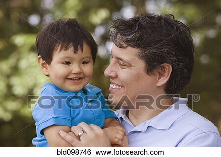 Stock Photograph - Smiling father holding baby boy. Fotosearch