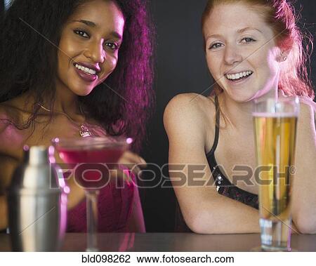 Stock Image - Smiling friends drinking cocktails. Fotosearch