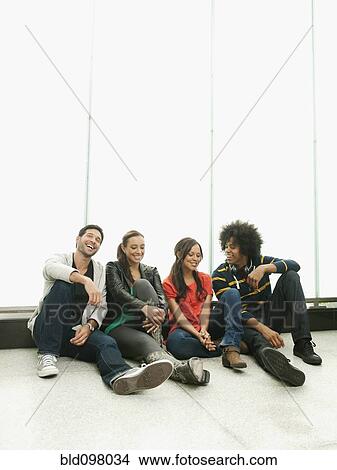 Picture - Smiling friends sitting on floor together. Fotosearch