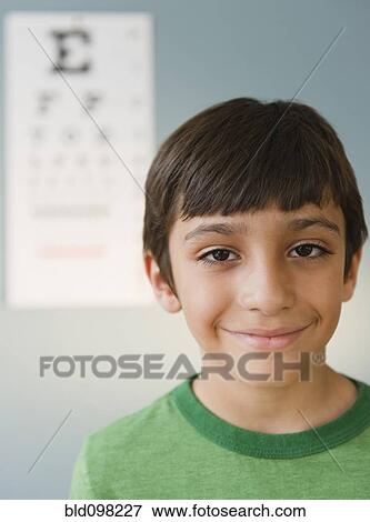 Stock Photo - Smiling Hispanic boy having eye test. Fotosearch
