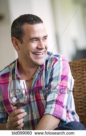 Stock Image - Smiling Hispanic man drinking wine. Fotosearch