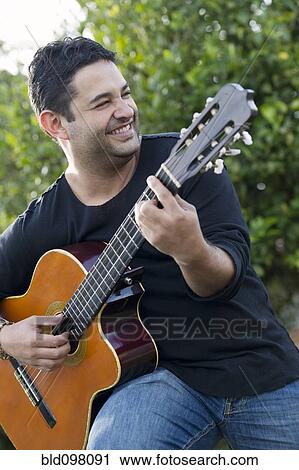 Smiling Hispanic man playing guitar View Large Photo Image Stock Image - Smiling Hispanic man playing guitar. Fotosearch