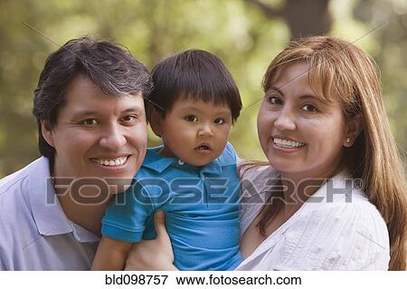 Stock Photo - Smiling Hispanic parents holding baby boy. Fotosearch