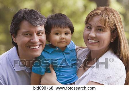 Stock Photo - Smiling Hispanic parents holding baby boy. Fotosearch