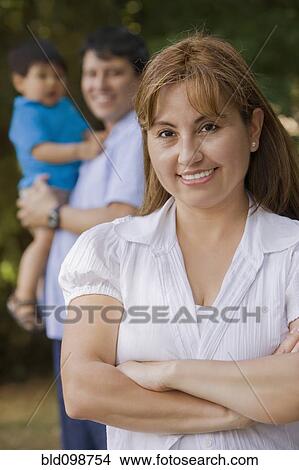 Picture - Smiling Hispanic woman outdoors with family. Fotosearch