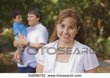 Stock Image - Smiling Hispanic woman outdoors with family. Fotosearch