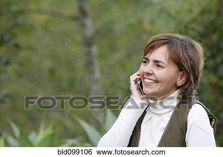 Stock Photograph - Smiling Hispanic woman talking on cell phone. Fotosearch