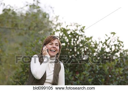 Stock Photography - Smiling Hispanic woman talking on cell phone. Fotosearch