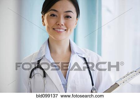 Stock Photo - Smiling Japanese doctor holding medical record. Fotosearch
